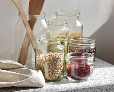 Kuru baklagillerin çeşitleri: böbrek fasulyesi, bezelye, cam kavanozlarda pişirilmemiş yeşil gram beyaz mutfak arka planı, sıfır atık, çevre dostu, dengeli diyet yiyecekler, sağlıklı temiz yiyecekler, vegan protein konsepti