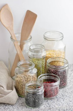 Kuru baklagillerin çeşitleri: böbrek fasulyesi, bezelye, cam kavanozlarda pişirilmemiş yeşil gram beyaz mutfak arka planı, sıfır atık, çevre dostu, dengeli diyet yiyecekler, sağlıklı temiz yiyecekler, vegan protein konsepti