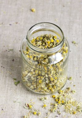 Çin fincanındaki papatya çayı ve kuru bitki çiçekleriyle dolu cam kavanoz, yukarıdan bakıldığında, naturopati, doğal tıp, uyku için iyileştirme içecekleri, cilt ve saç bakımı konsepti.