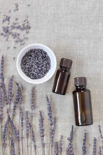 Lavender essential oil, dry herb in a bowl with flowers nearby, closeup, from above overhead top view, natural medicine, naturopathy, organic cosmetics, sleep tea, skin and hair care concept