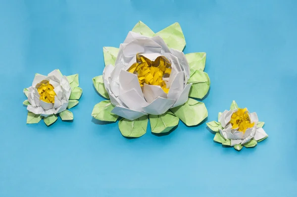 Origami: tre vita lotuses på blå bakgrund av papper lak Royaltyfria Stockfoton