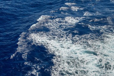 Üzerinde beyaz deniz köpüğü olan mavi okyanus dalgası.