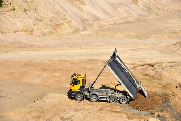 Dump truck unloading earth sand in quarry. Recovering the landscape around the open pit. Process of restoring land. Mine reclamation occurs once mining sand is completed.