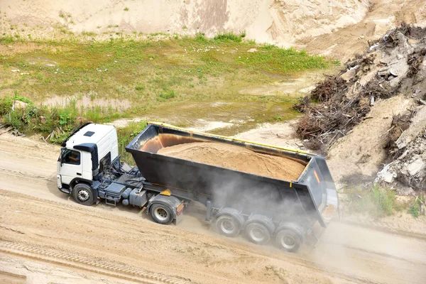 Dump truck transports sand in open pit mine. In the production of concrete, concrete for the construction using coarse sand. Quarry in which sand and gravel is excavated from ground. Mining industry