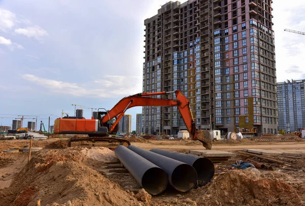 Excavator dig the trenches at a construction site. Trench for laying external sewer pipes. Sewage drainage system for a multi-story building. Civil infrastructure pipe, water lines and sanitary storm