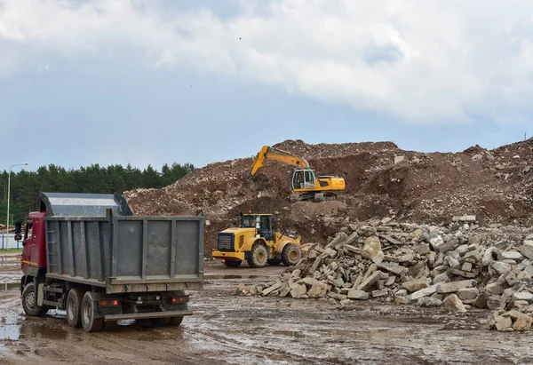 Excavator, dump truck and wheel loader at landfill for disposal of construction waste and concrete crushing. Recycling concrete and asphalt from demolition. Heavy machinery works in mining quarry