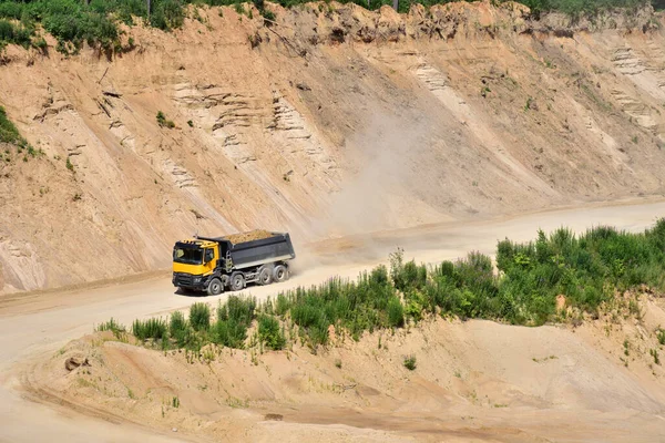 Dump truck transports sand in open pit mine. In the production of concrete, concrete for the construction using coarse sand. Quarry in which sand and gravel is excavated from ground. Mining industry