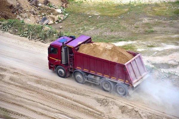 Dump truck transports sand in open pit mine. In the production of concrete, concrete for the construction using coarse sand. Quarry in which sand and gravel is excavated from ground. Mining industry