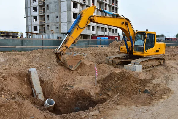 Excavator dig the trenches at a construction site. Trench for laying external sewer pipes. Sewage drainage system for a multi-story building. Civil infrastructure pipe, water lines and sanitary storm