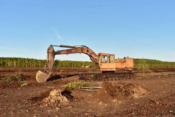 Excavator digging drainage ditch in peat extraction site. Drainage of peat bogs and destruction of trees. Drilling on bog for oil exploration. Mining peatlands. Wetlands declining and under serious threat