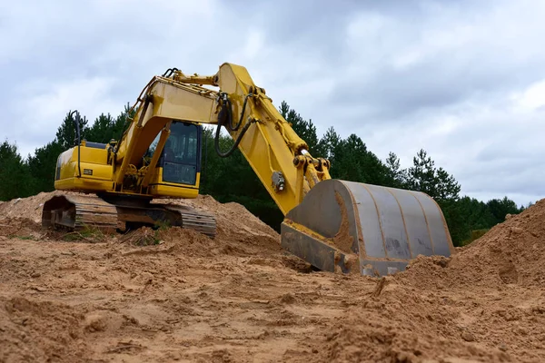 Excavator clearing forest for new development and road work. Backhoe for forestry work. Tracked heavy power machinery for forest and peat industry. Logging, road construction in forests