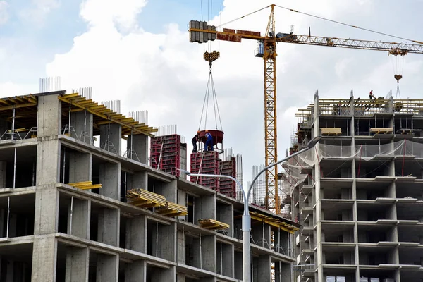 Preparing to pour a bucket of concrete into formwork.Tower crane lifting cement bucket during construction a multi-storey residential building. Construction cranes and builders in action