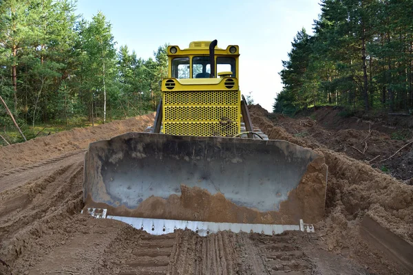 Dozer during clearing forest for construction new road . Yellow Bulldozer at forestry work Earth-moving equipment at road work, land clearing, grading, pool excavation, utility trenching