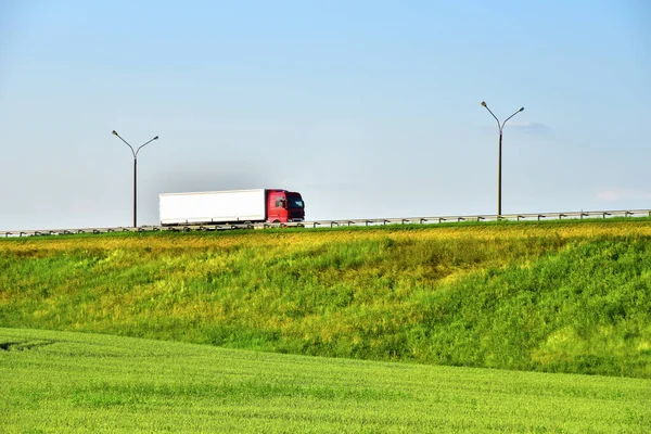 Semi-trailer truck driving along highway on blue sky background. Goods Delivery by roads