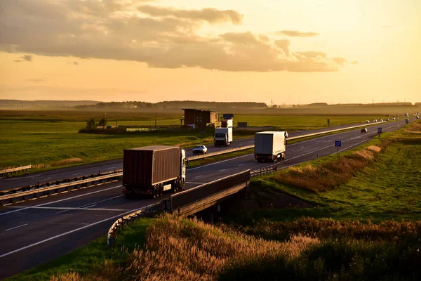 Trucks with Semi-trailer driving on highway on sunset background. Goods Delivery. Services and Transport logistics. Out of focus, possible granularity, motion blur.