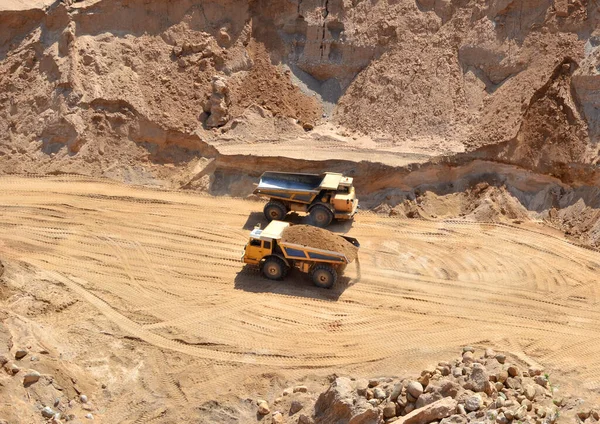 Mining trucks transports sand in an open pit. View of the quarry where sand is mined. Mining industry concept. Out of focus, possible granularity, motion blur