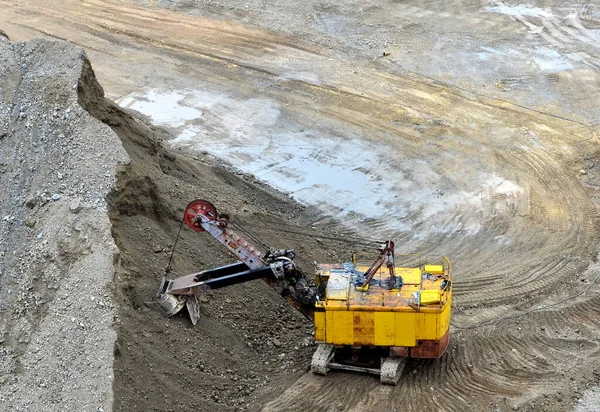 Excavator with electric shovel loading the rocks in mining truck at quarry. Haul truck transports minerals in the open pit. Open-cast mining of extracting rock or minerals from the earth.