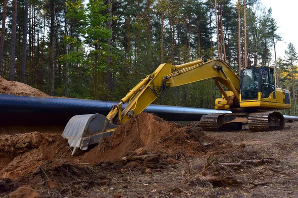 Excavator during earthwork for laying Crude oil and Natural gas pipeline in forest area.  Installation of  gas and crude oil pipes in ground. Construction of the gas pipes to new LNG plant