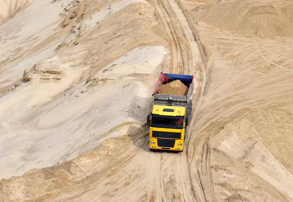 Truck with tipper semi trailer transported sand from the quarry. Dump truck working in open pit mine. Sand and gravel is excavated from ground. Mining industry