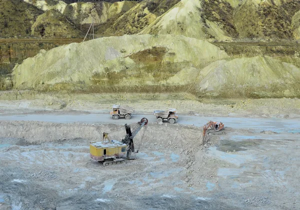 Aerial top view of mining industry. Excavator in quarry loads rock into a mining truck. Excavators and trucks work in a chalk open pit. Small roughness sharpness, possible granularityAerial top view of mining industry. Excavator in quarry loads rock