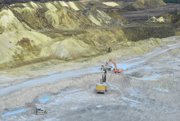 Aerial top view of mining industry. Excavator in quarry loads rock into a mining truck. Excavators and trucks work in a chalk open pit. Small roughness sharpness, possible granularityAerial top view of mining industry. Excavator in quarry loads rock
