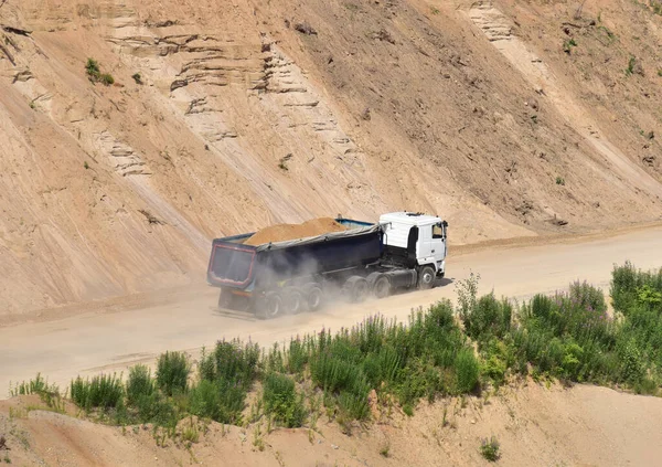 Truck with tipper semi trailer transported sand from the quarry. Dump truck working in open pit mine. Sand and gravel is excavated from ground. Mining industry