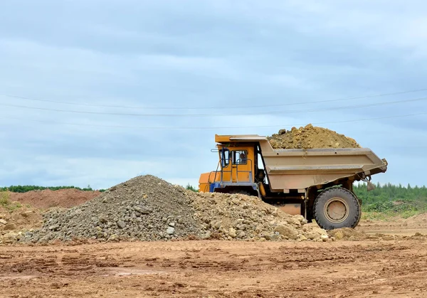 Mining truck and excavators working in the limestone open-pit. Loading and transportation of minerals in the dolomite mining quarry