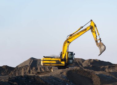 Kazıcı açık maden ocağında toprak hareketliliği üzerinde çalışıyor. Kepçeler taş ocağında çakıl kazıyor. Taş ocağı için inşaat malzemeleri ve makineler. Çakıl ve beton atıkların geri dönüşümü