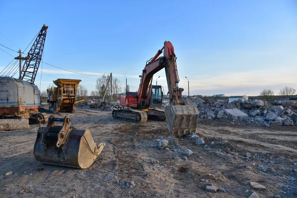 Excavator and Mobile Stone crusher during the destruction of concrete and hard rock at landfill. oncrete waste after demolition on construction site. Recycle and Reuse Concrete concept