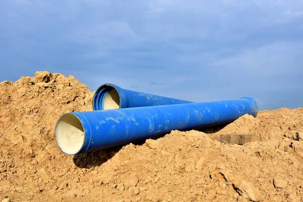 Blue concrete drainage pipes at the construction site. Laying of underground storm sewer pipes. Installation of water main, sanitary sewer. Installation of concrete sewer wells in the ground