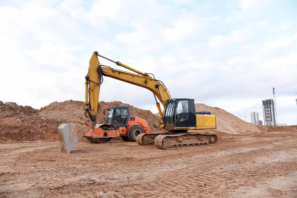 Soil Compactor the leveling soil at construction site. Excavator and vibration single-cylinder road roller during the construction of roads