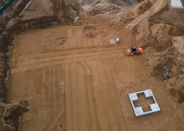 Drone view of construction site. Vibration road roller leveling the ground for construct of foundation for residential building. Soil Compactor compresses the soil under the formwork. Soft focus