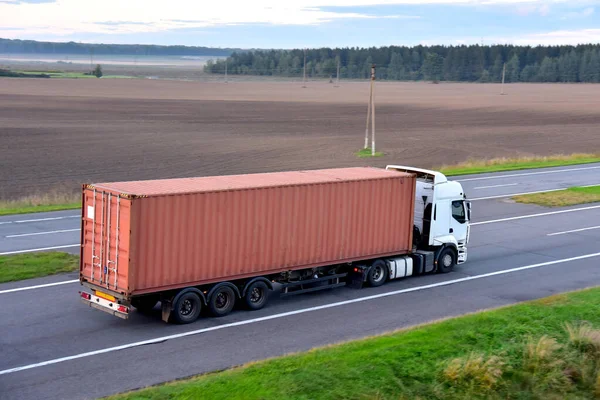 Semi Truck transport the sea container on highway. Shipping Containers Delivery by road, Maritime Services and Transport logistics. Soft focus possible granularity