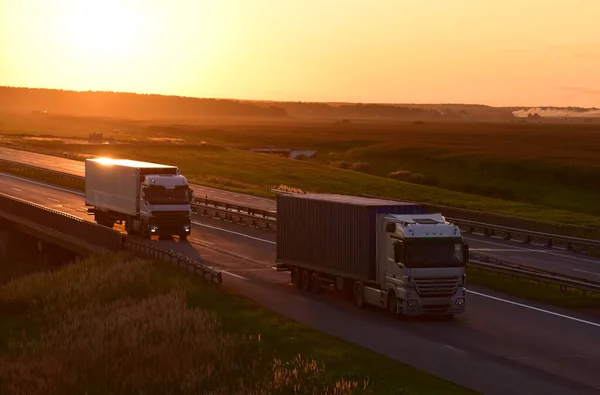 Semi-trailer truck by driving along highway on sunset background. Goods delivery by roads. Services and Transport logistics. Trucks and lorry on road