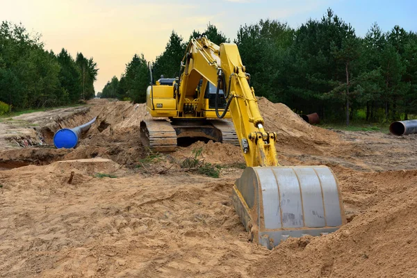 Excavator during earthwork for laying Crude oil and Natural gas pipeline in forest area.  Installation of  gas and crude oil pipes in ground. Construction of the gas pipes to new LNG plant