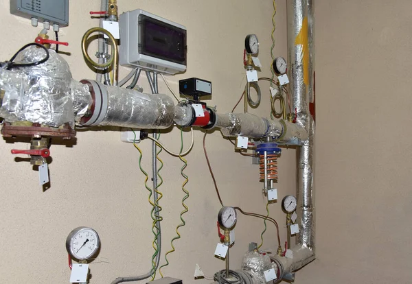 Heating system in boiler room at home. Round mechanical pressure gauge for measuring pressure and temperature control. Gauges near the heating pipes with insulation coating. Oil and gas pipeline