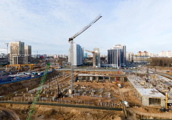 Drone view of a large construction site. Tower cranes in action on fog background. Housing renovation concept. Crane during formworks. Construction the buildings and multi-storey residential homes