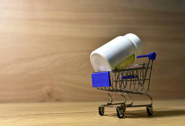 Pill bottle in a shopping basket. Economy concept of spending money on medicines and pills. Medical pill for maintaining and improving health in trolley. Shopping cart with pills