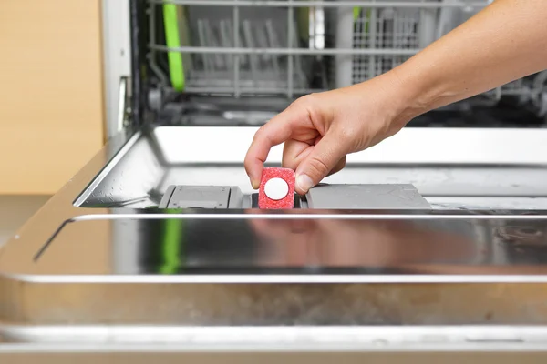 Woman putting tablet in dishwasher detergent box — Stock Photo, Image