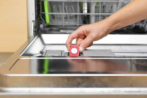 Žena uvedení tabletu v myčka nádobí detergent box Stock Snímky