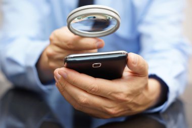 Mobil akıllı telefon olan büyüteç kullanarak bir iş adamı. Pho