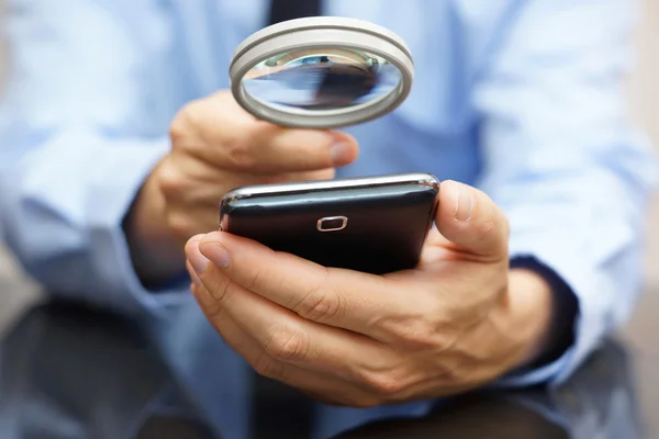 Businessman using mobile smart phone with magnifying glass . Pho — Stock Photo, Image