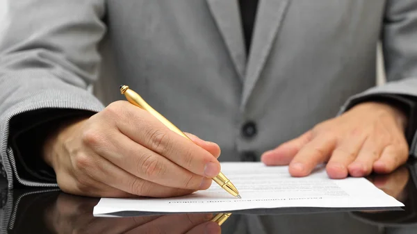 Zakenman is herziening van overeenkomst met gouden pen Stockfoto