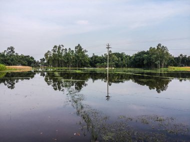 Suyun görüntüsü güzel mavi gökyüzünü ve elektrik hattı kulesini yansıtıyor..