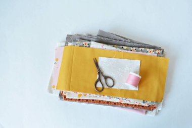 Pamuk kumaşlar, küçük makas, beyaz üzerine pembe iplik.