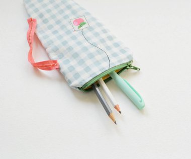 El yapımı fermuar kesesi ve kalemler beyazın üzerine.