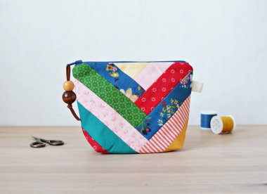 Renkli yama kavramları çantası, geçmişe dönük makas ve iplik makaraları beyaz masanın üzerinde.