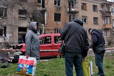 29 Kasım 2025 'te Ukrayna' nın başkenti Kyiv 'de Rus hava saldırısında hasar gören bir apartmanın önündeki avluda oturan vatandaşlar görülüyor.. 