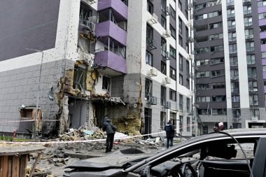 29 Kasım 2025 'te Ukrayna' nın başkenti Kyiv 'de Rus hava saldırısında hasar gören bir apartmanın önündeki avluda oturan vatandaşlar görülüyor.. 