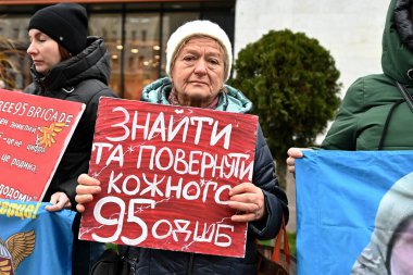 İnsanlar Ukraynalı savaş esirlerini desteklemek için miting sırasında pankart taşıyorlar.